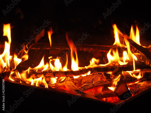 Orange flames on firewood, a dying fire on a dark background. Beautiful close-up background, selective focusing.