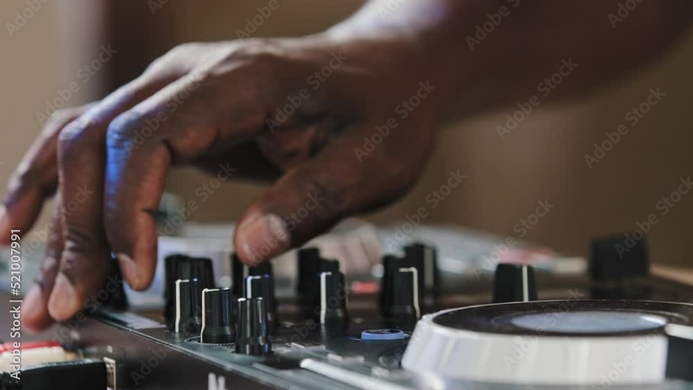 Close-up unrecognizable DJ man African male finger using mixer controller desk in club musical studio on stage celebrating turns up volume rotates buttons creates audio effects play live music disco Close-up unrecognizable DJ man African male finger using mixer controller desk in club musical studio on stage celebrating turns up volume rotates buttons creates audio effects play live music disco