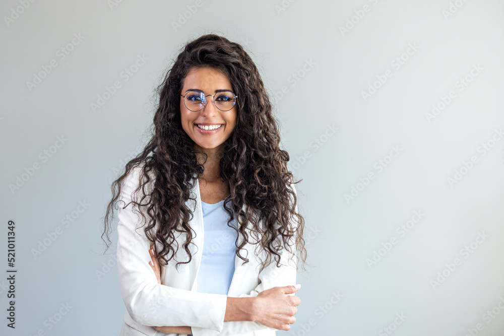 Portrait of young smiling woman looking at camera with crossed arms. Happy girl standing in creative office. Successful businesswoman standing in office with copy space. Portrait of young smiling woman looking at camera with crossed arms. Happy girl standing in creative office. Successful businesswoman standing in office with copy space.