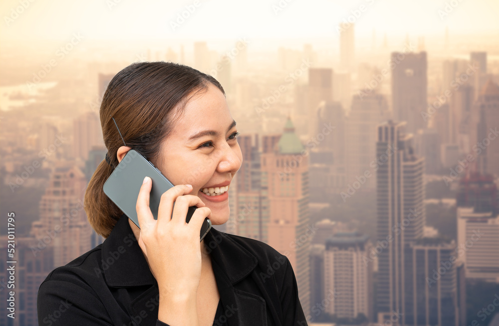 Asian businesswoman talking on mobile phone with cityscape on background Asian businesswoman talking on mobile phone with cityscape on background