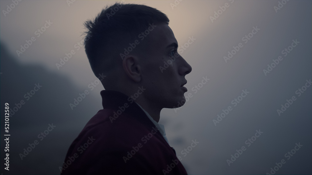 Stressed guy standing on sea beach at sunrise. Tired man breathing ocean air Stressed guy standing on sea beach at sunrise. Tired man breathing ocean air