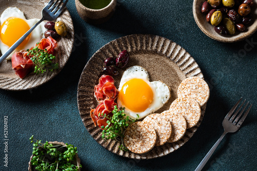 Romantic breakfast - fried eggs in the shape of a heart and olives. Healthy breakfast. Rice cakes with eggs and hamon. Keto diet breakfast. Top view.