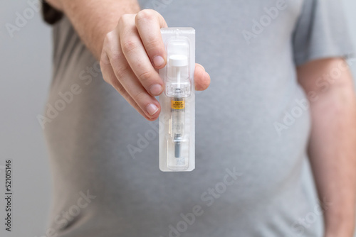 Obese young man holds an anticoagulant syringe to apply after bariatric surgery.