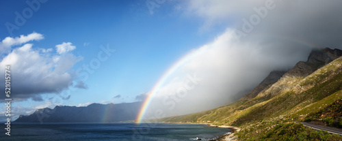 A rainbow and storm over the Kogelberg Mountains along the coastline from Clarence Drive between Gordon s Bay and Rooi-Els on the eastern part of False Bay  Cape Town  Western Cape  South Africa.