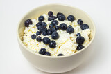 Cottage cheese with blueberries on a white background. Useful and tasty breakfast.