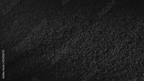 Carbon powder or black charcoal powder. Dark textured background. Volcano dust moving on surface, close-up