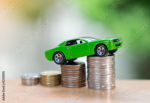 Car climb coin stack to hight on out of focus background.