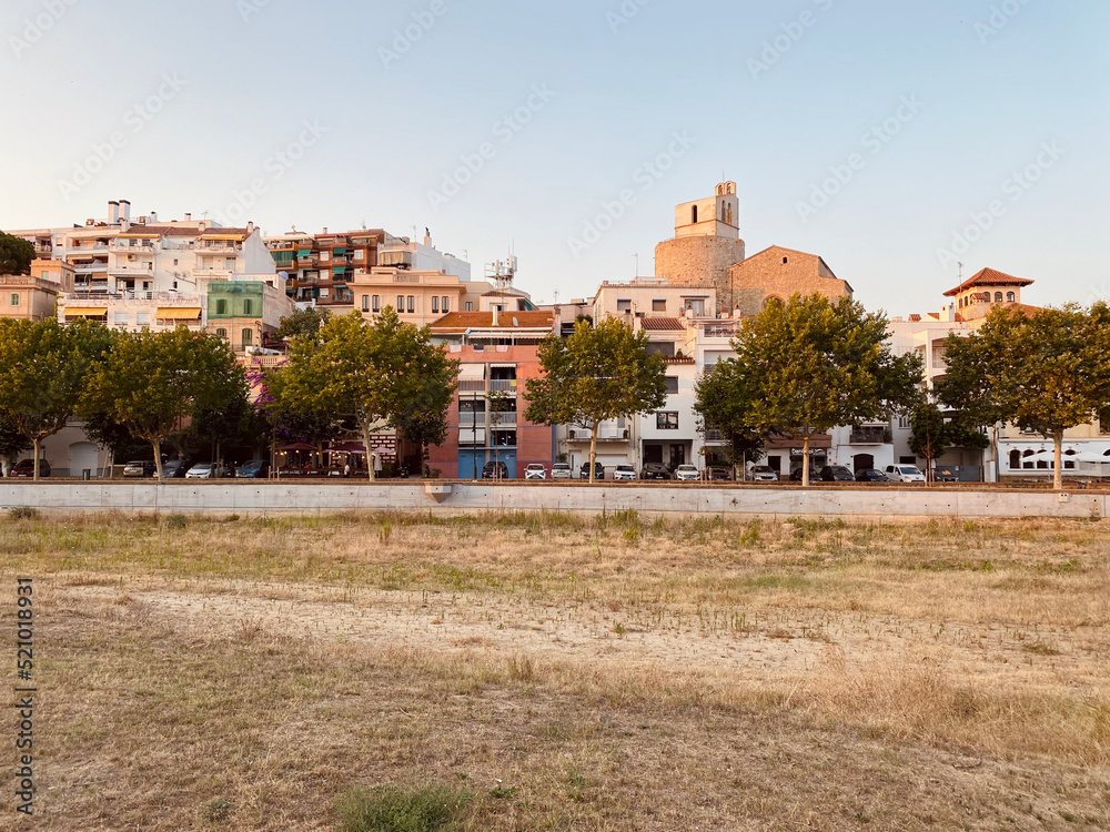Sant Pol de Mar town on the Maresme coast. Located in the province of Barcelona, ​​Catalonia, Spain. Charming towns in the Mediterranean. Green meadow with town in the background. Space for text.