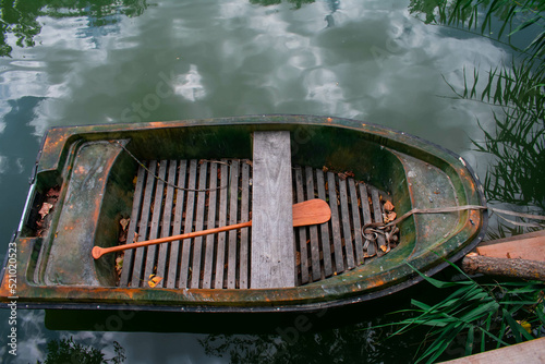 Rusty old boat on the branch of the river Danube in Serbian-Hungarian border with wooden paddle inside and reflection of the cloudy sky in the water shot with Nikon D3400