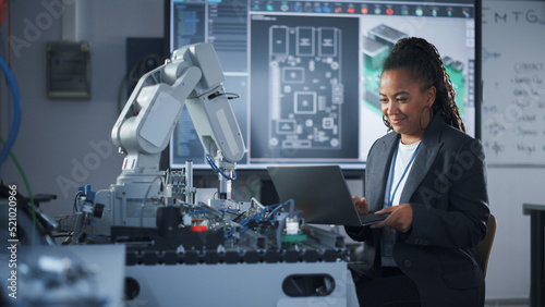 Photography Black Developer Works with Laptop, Writing Code for Robot Arm