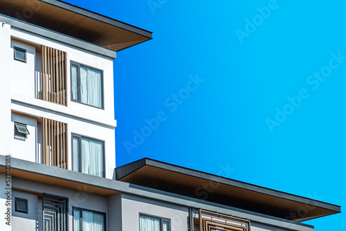 Fragment of Modern residential hotel with flat buildings exterior. Detail of New luxury house and home complex. Part of City Real estate property and condo architecture. Copy space. Blue sky