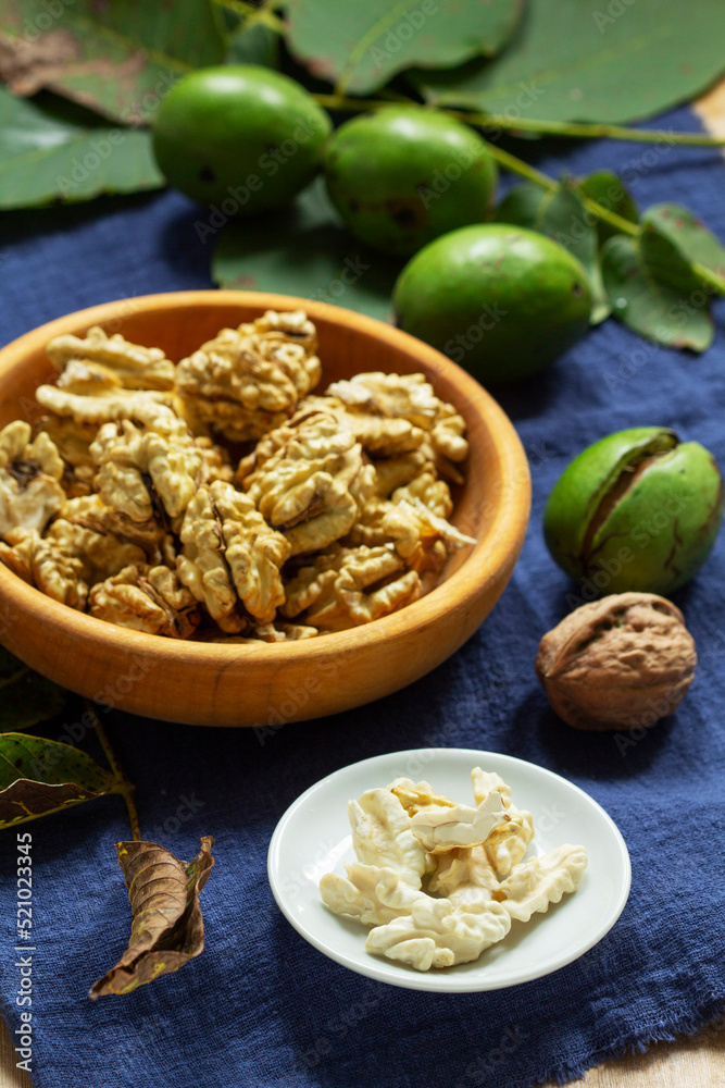 Young walnuts, shelled and in shell, walnut leaves. Rustic style.
