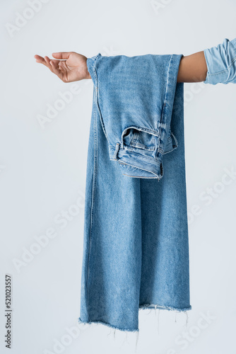 cropped view of african american woman holding blue jeans isolated on grey