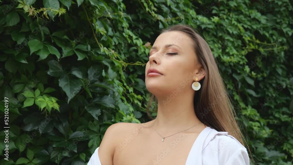 Portrait of a young beautiful woman on a background of green foliage. Woman in a white shirt outdoors in the jungle Portrait of a young beautiful woman on a background of green foliage. Woman in a white shirt outdoors in the jungle