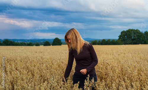 Portrait young caucasian woman walking in corn, grain field. Agriculture concept