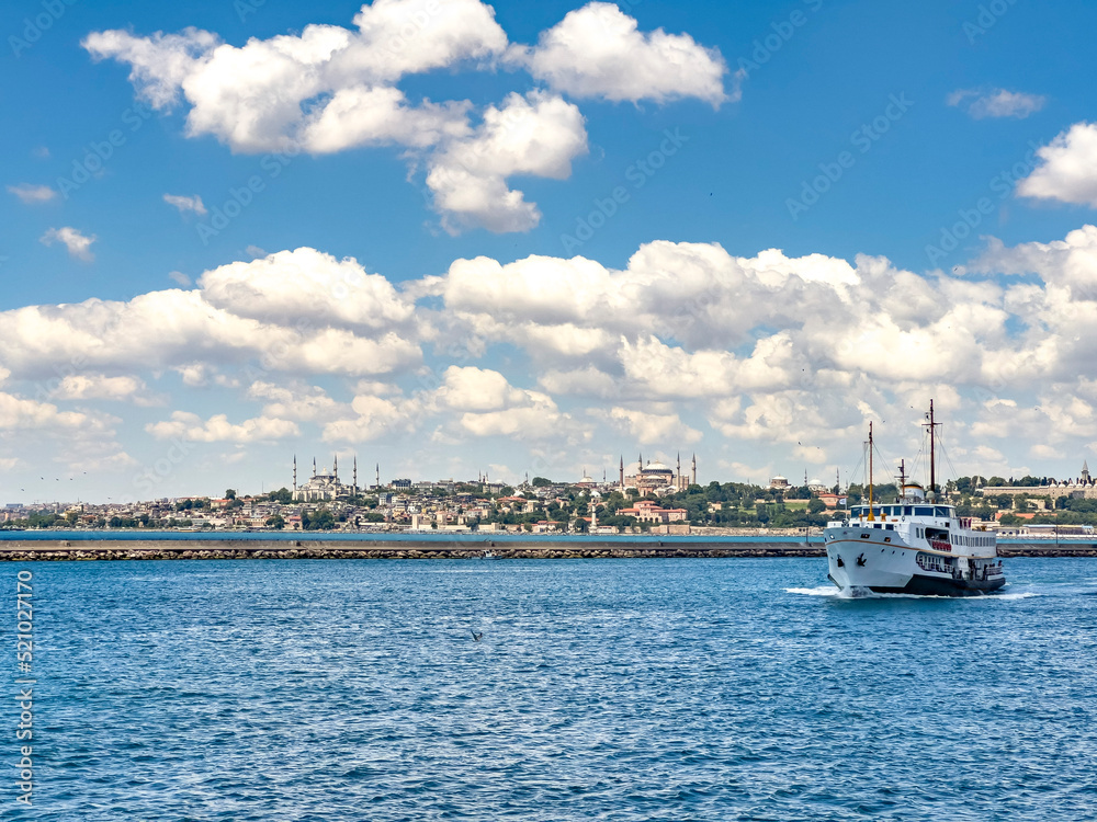 Traditional old ferry moving towards Kadikoy with Topkapi Palace and Blue Mosque landmark view in Istanbul on a sunny day. Beautiful travel destination postcard, poster banner background. 