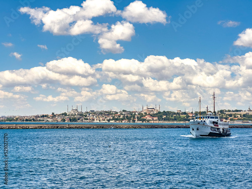 Traditional old ferry moving towards Kadikoy with Topkapi Palace and Blue Mosque landmark view in Istanbul on a sunny day. Beautiful travel destination postcard, poster banner background. 
