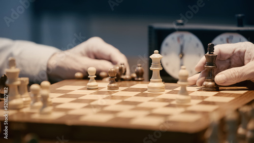 Fotografering partial view of senior men playing chess on blurred chessboard