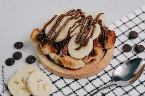 Croffle, Croissant Waffle Korea pastry. Croffle with different sweet topping banana slice and chocolate sauce served in wooden plate. Selective focus.