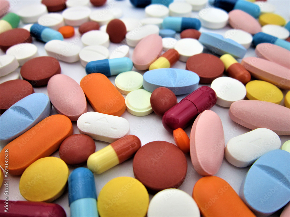 Different colored drugs and pills on the white laboratory table. Creative healthcare of medicine concept. Close the capsule stack. Flat laying. Different colored drugs and pills on the white laboratory table. Creative healthcare of medicine concept. Close the capsule stack. Flat laying.