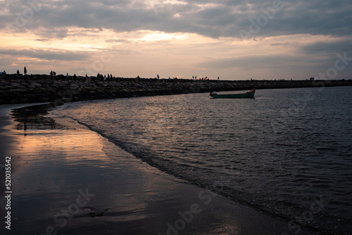 sunset over the sea with a fishing boat on the dock