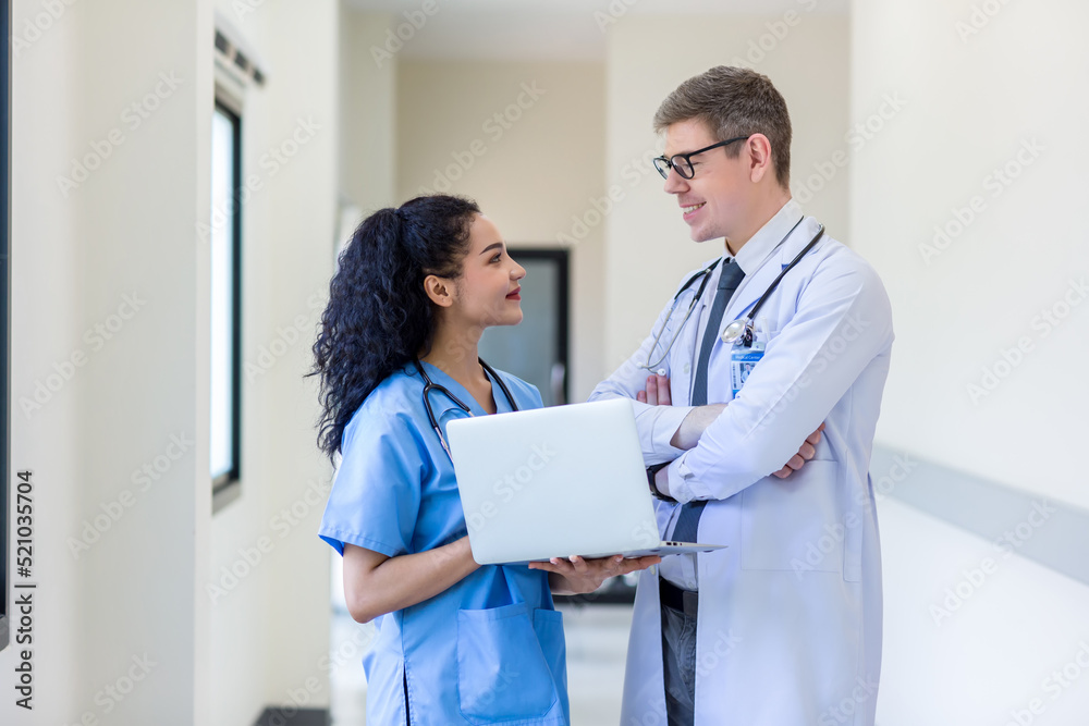 Clinicians in uniform standing and looking of computer monitor, discussing medical document and consulting. Doctor and nurse working on laptop in medical office. Professional medical work with Laptop Clinicians in uniform standing and looking of computer monitor, discussing medical document and consulting. Doctor and nurse working on laptop in medical office. Professional medical work with Laptop
