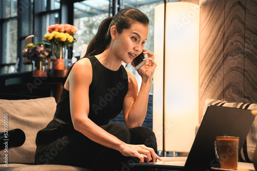 Business woman using a mobile phone and a laptop to work online