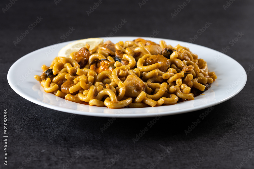 Traditional Spanish fideua. Noodle paella on black background Traditional Spanish fideua. Noodle paella on black background