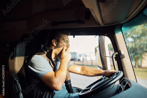 Foto Tired truck driver yawning behind the steering wheel.