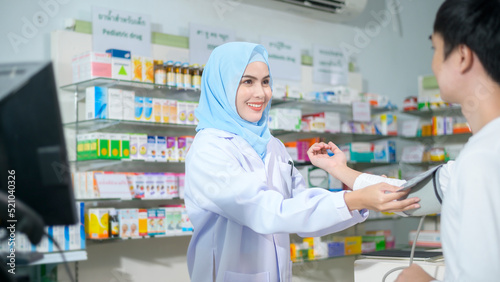 Female muslim pharmacist counseling customer about drugs usage in a modern pharmacy drugstore.