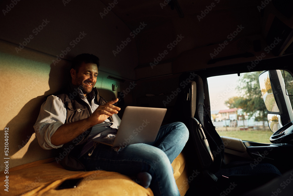Happy truck driver talking during video call from vehicle cabin.