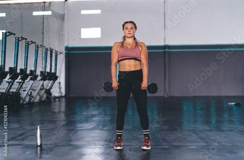 Determined Caucasian woman in active sportswear have cardio training in gym using sportive equipment, strong female using dumbbells for weightlifting workout on slimming and muscles strength