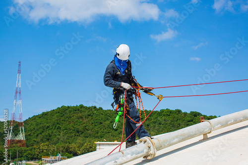 Male worker inspection wearing safety first harness rope safety line working at a high place on tank roof spherical gas