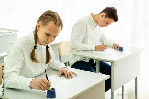 Two young students  an attractive dark-haired man and a blonde woman  are working on a project in the classroom  sitting at the table of a light class. High quality photo