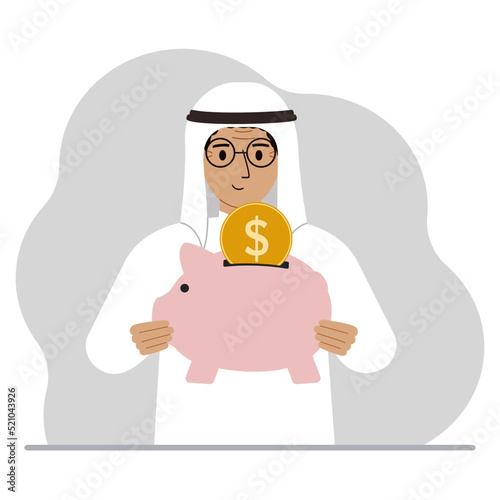 Happy muslim man holds a piggy bank, a coin falls into the piggy bank. The concept of saving finance, savings, investing finances.
