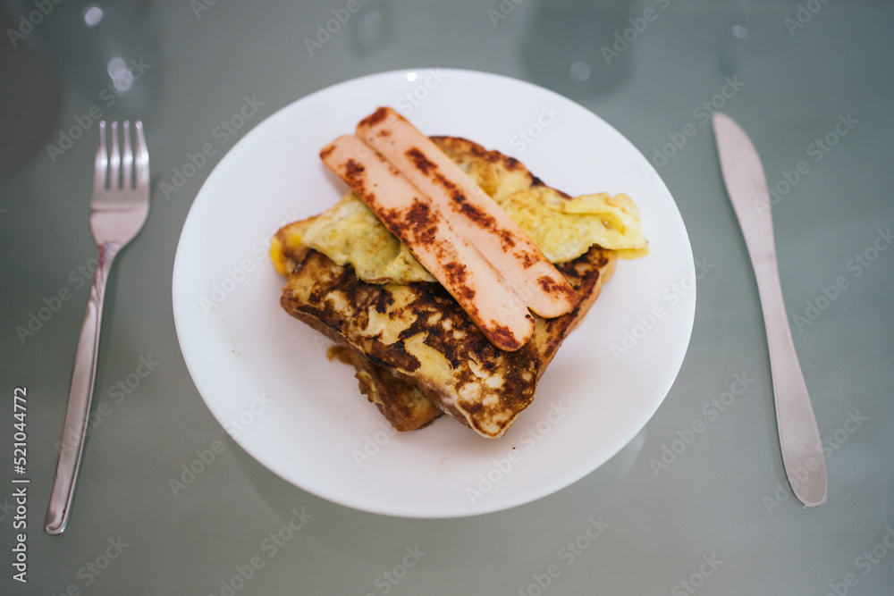 Frensh toast with sausage in white plates and cuttery in isolated glass background Frensh toast with sausage in white plates and cuttery in isolated glass background