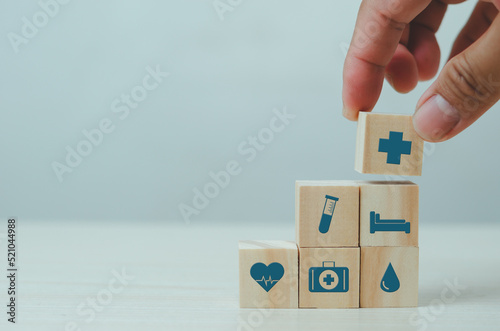 Hand put wooden cubes with insurance health care medical symbol on table copy space.Business concepts.