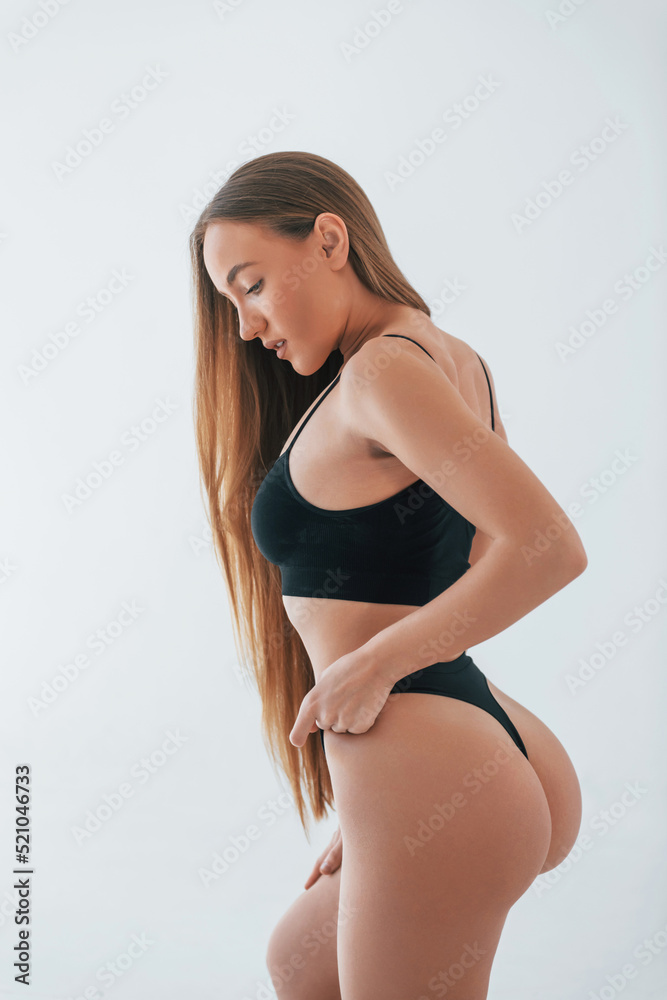 Model is against white background. Woman in underwear with slim body type is posing in the studio Model is against white background. Woman in underwear with slim body type is posing in the studio