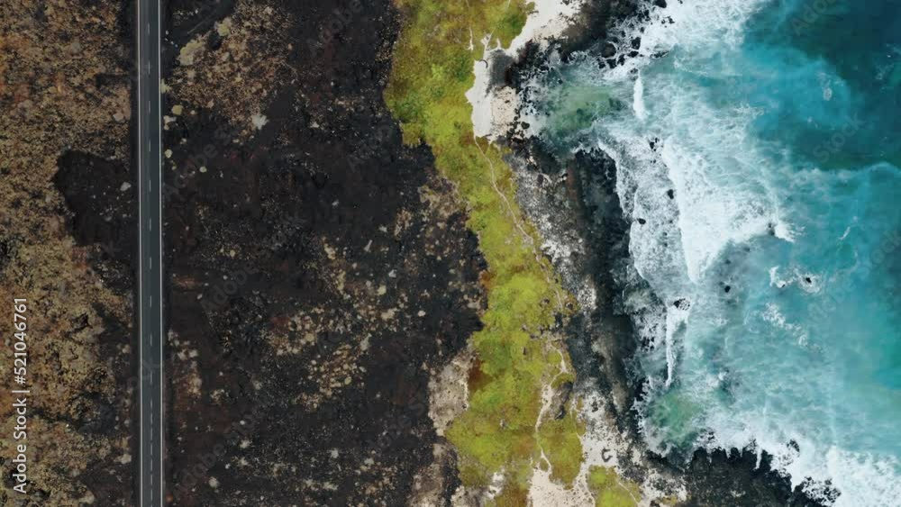 Aerial of mountain coastal road in volcanic lava landscape along Atlantic Ocean coast. Lanzarote, Canary Islands, Spain
