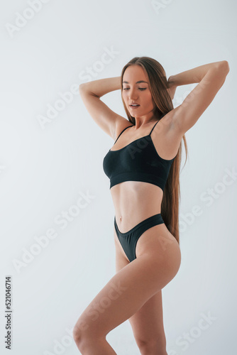 Beautiful female with brown hair. Woman in underwear with slim body type is posing in the studio