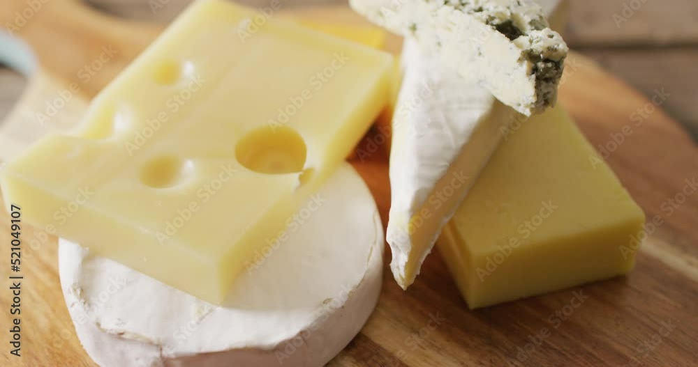 Video close up of assorted hard and soft cheeses on wooden chopping board