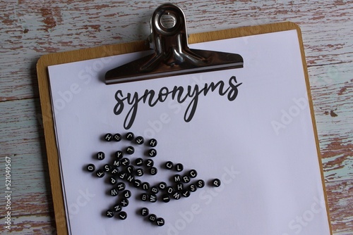 Top view image of paper clipboard with text synonyms and alphabet beads. photo