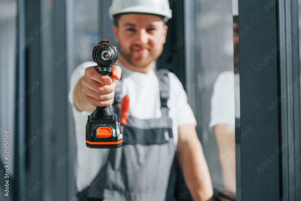 Working with windows. Repairman is indoors in the modern room Working with windows. Repairman is indoors in the modern room