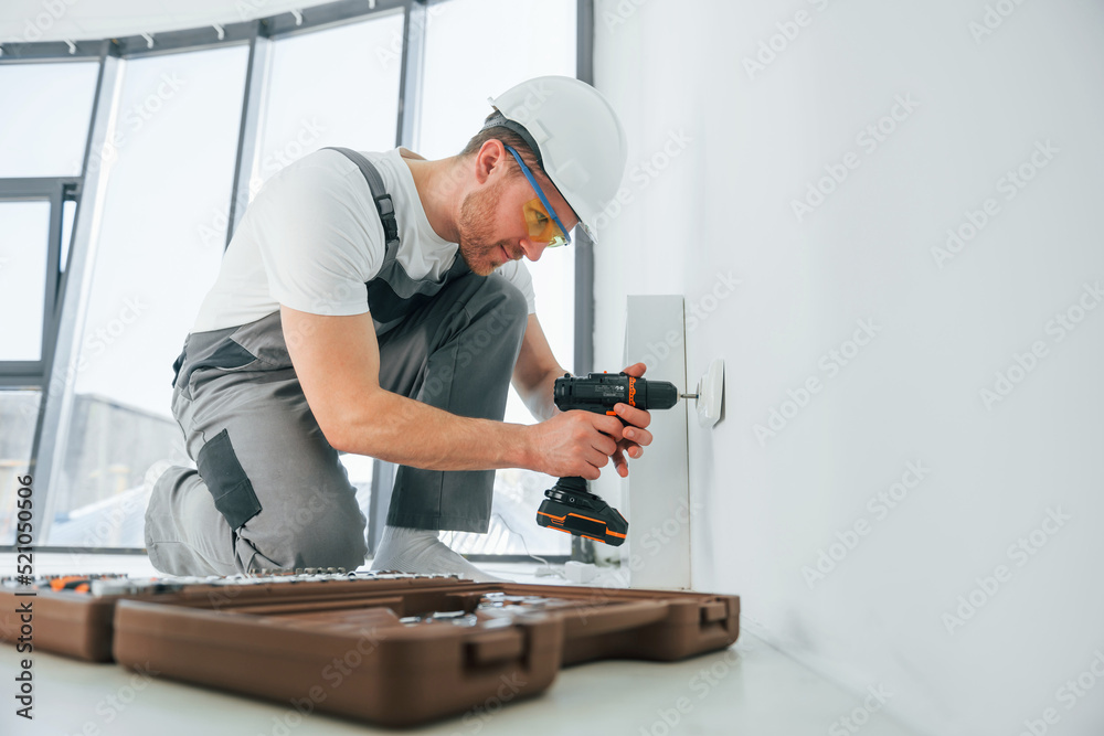 Side view. Repairman is working indoors in the modern room Side view. Repairman is working indoors in the modern room