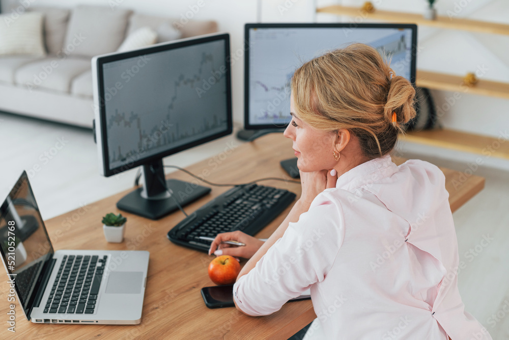 Monitoring the market. Female stock broker in formal wear is working in the office Monitoring the market. Female stock broker in formal wear is working in the office