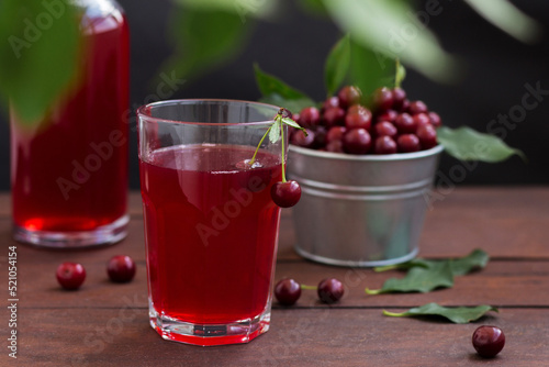 cherry juice in a glass with cherries on a wooden background