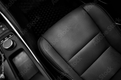 Top view of luxury sport car front passenger leather seat with detail high end fabric and stitch texture along with blurred control button panel. Design element and black car interior background. photo