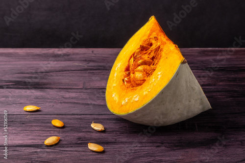 cut-out pumpkin segment with seeds on a dark table
