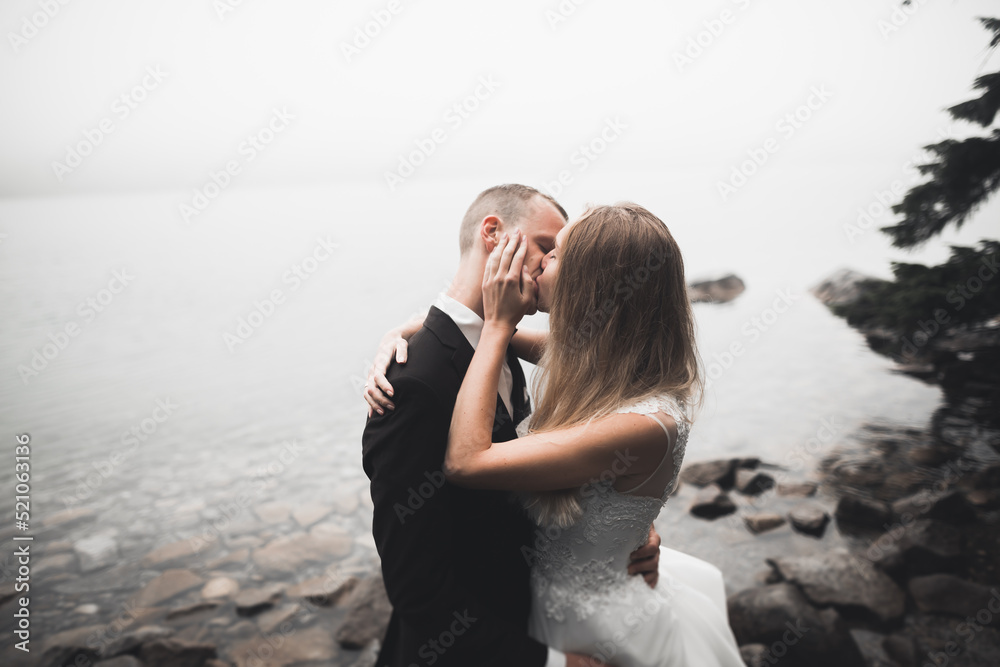 Happy and romantic scene of just married young wedding couple posing on beautiful beach
