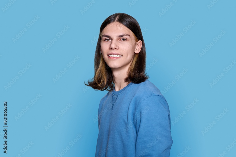 Headshot portrait of teenage guy looking at camera on blue background Headshot portrait of teenage guy looking at camera on blue background